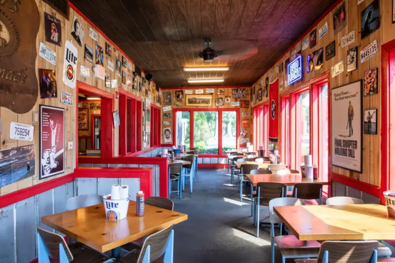 A long hall with different posters on walls and red windows, wooden tables and brown chairs